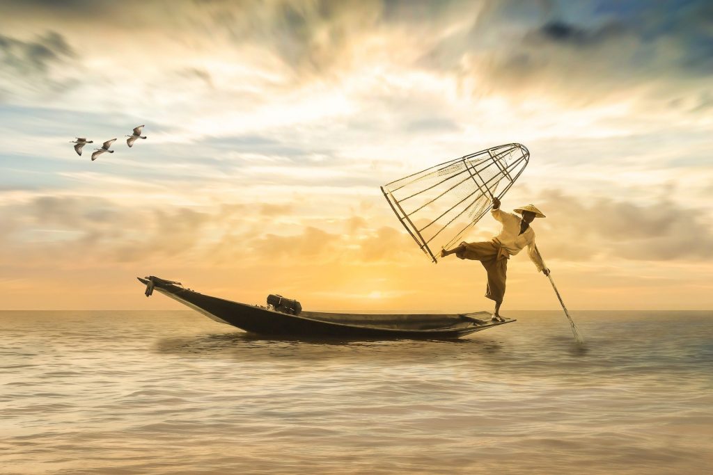 船に乗り魚を捕る漁師の画像